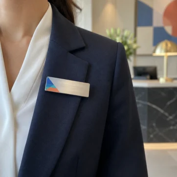 Identyfikatory imienne – srebrny identyfikator na marynarce pracownika recepcji